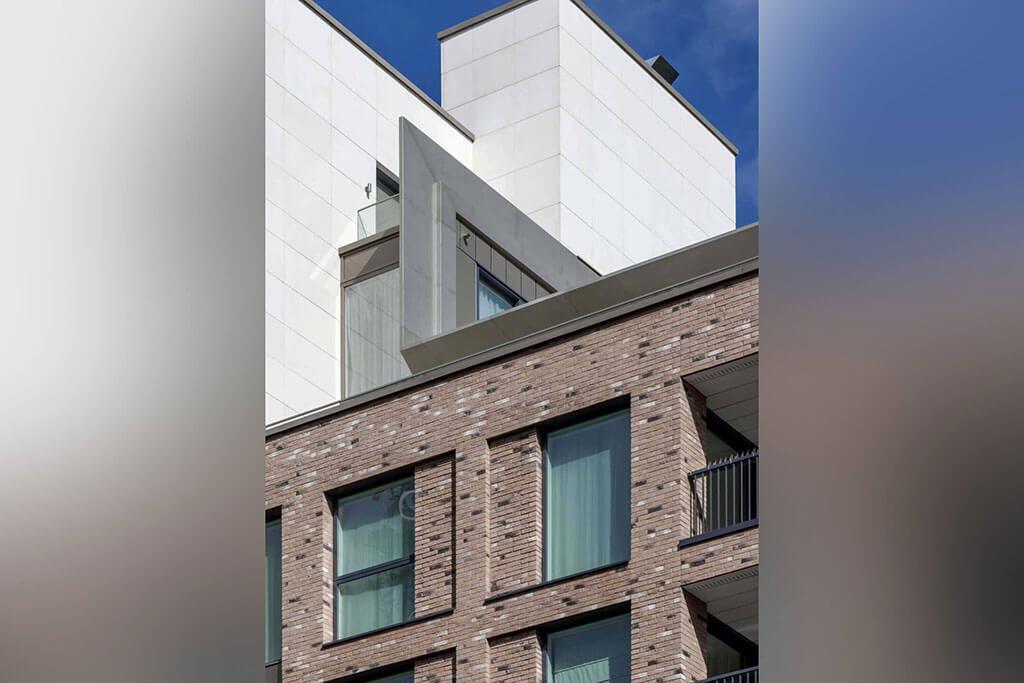 Okna drewniano – aluminiowe, okna balkonowe, kolor antracyt, widok od zewnątrz na budynek apartamentowca, elewacja z cegły i płyt piaskowca.