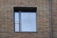 Okna drewniano – aluminiowe, kolor antracyt, widok z zewnątrz na pojedyncze okno balkonowe, duża fixa i wąska cześć otwierana z widoczną balustradą.